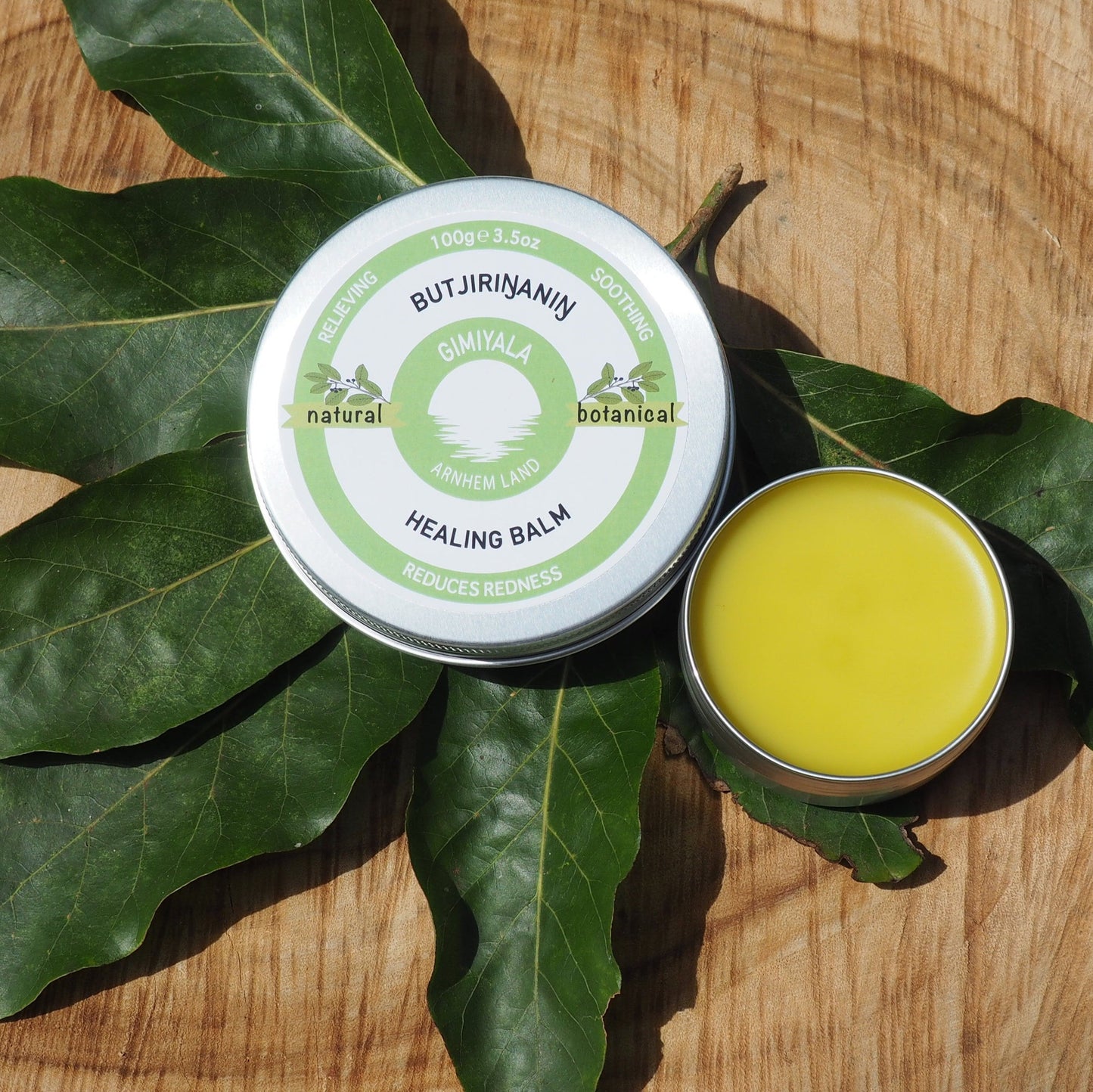 Healing balm container with green leaves on a wooden surface